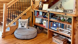 Eine Holztreppe mit einem Schild 'Beaver Lake', einem Kissen mit der Aufschrift 'Nur für den Hund' und einem Bücherregal mit verschiedenen Gegenständen.