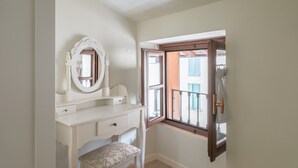 A white vanity with a mirror and a bench, a window with a view of a balcony, and a door leading outside. - Angelina s House in Iseo (Iseo)