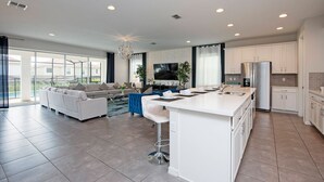 Una cocina moderna con armarios blancos, una isla grande y una zona de comedor con sofá azul.