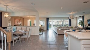 Amplia sala de estar con mesa de comedor, sofás e isla de cocina.