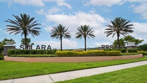 Zona ajardinada con un cartel que dice 'SOLARA RESORT', rodeada de palmeras y césped cuidado.
