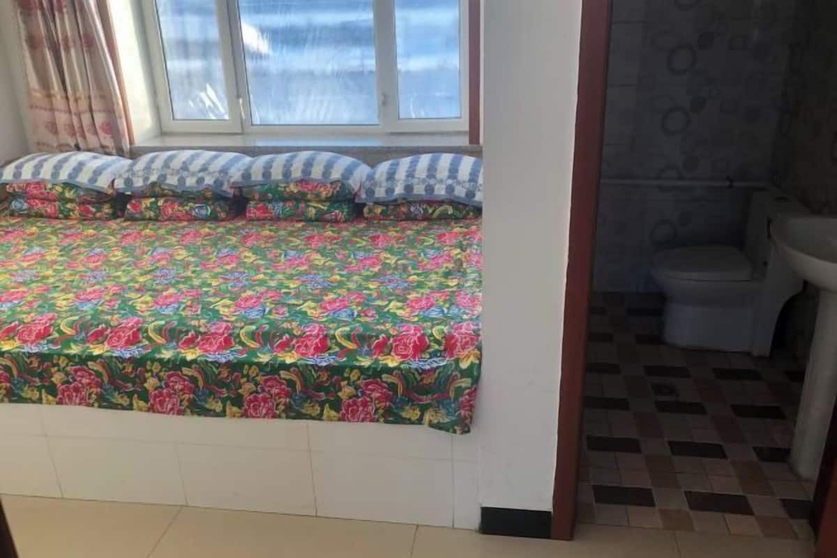A room with a bed, a window, a bathroom with a toilet and sink.