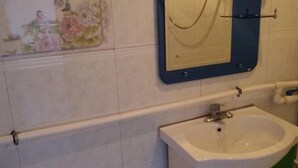 A bathroom with a white sink, a mirror with a blue frame, and a floral tile design on the wall. - Mohe Yujia Inn (Mohe)