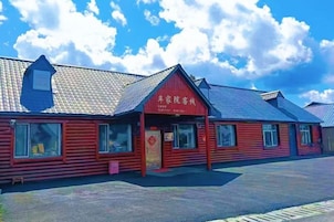 A red building with a sign, windows, and a tiled roof.