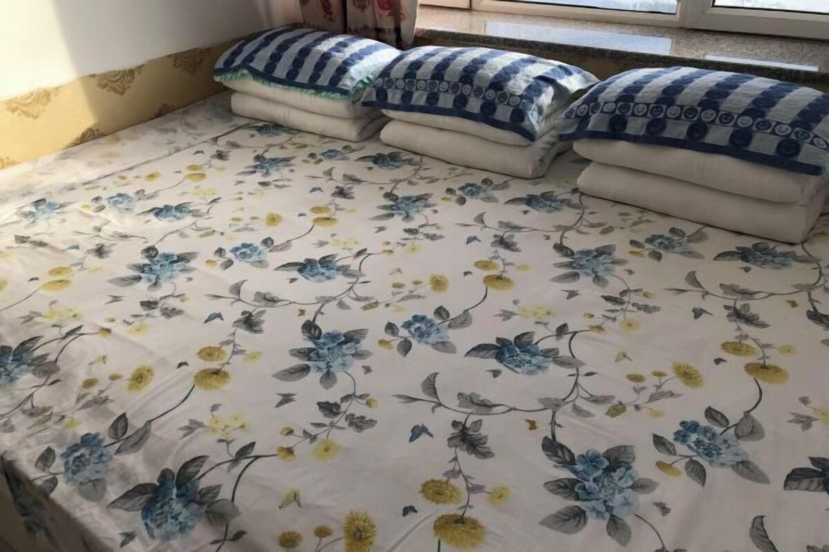 A bed with a floral bedspread and several pillows with a blue and white pattern.