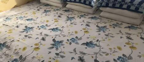 A bed with a floral bedspread and several pillows with a blue and white pattern.