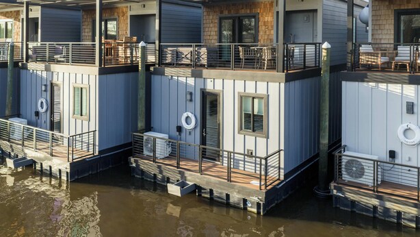A waterfront property with multiple levels, outdoor seating, and a dock. - Flourish at The Cove Riverwalk Villas (Wilmington)