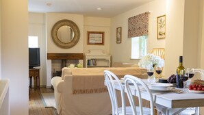 Un coin repas avec une table dressée pour deux personnes, une cheminée et un téléviseur en arrière-plan.