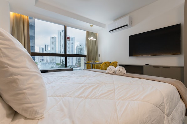 Una habitación de hotel moderna con una cama grande, un televisor de pantalla plana y vistas a la ciudad.
