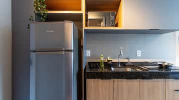 Una cocina moderna con microondas empotrado, refrigerador de acero inoxidable, armarios de madera y encimera de granito.