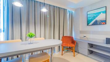 Uma zona de refeições moderna com uma mesa branca, cortinas cinzentas e uma cadeira vermelha.