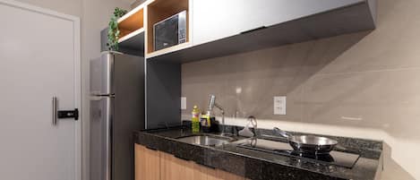 A modern kitchen with a stainless steel refrigerator, a double sink, and a built-in stove.