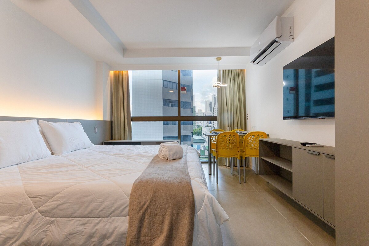 A hotel room with a bed, a TV, a desk, and a chair.