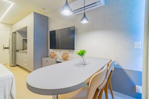 Une cuisine moderne dotée d’un grand îlot central, d’appareils électroménagers intégrés, de luminaires suspendus et d’un téléviseur à écran plat.