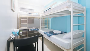 A bunk bed room with a desk and chair, a small table with a plant, and a window with blinds. - Catlea Inn (Pasay)