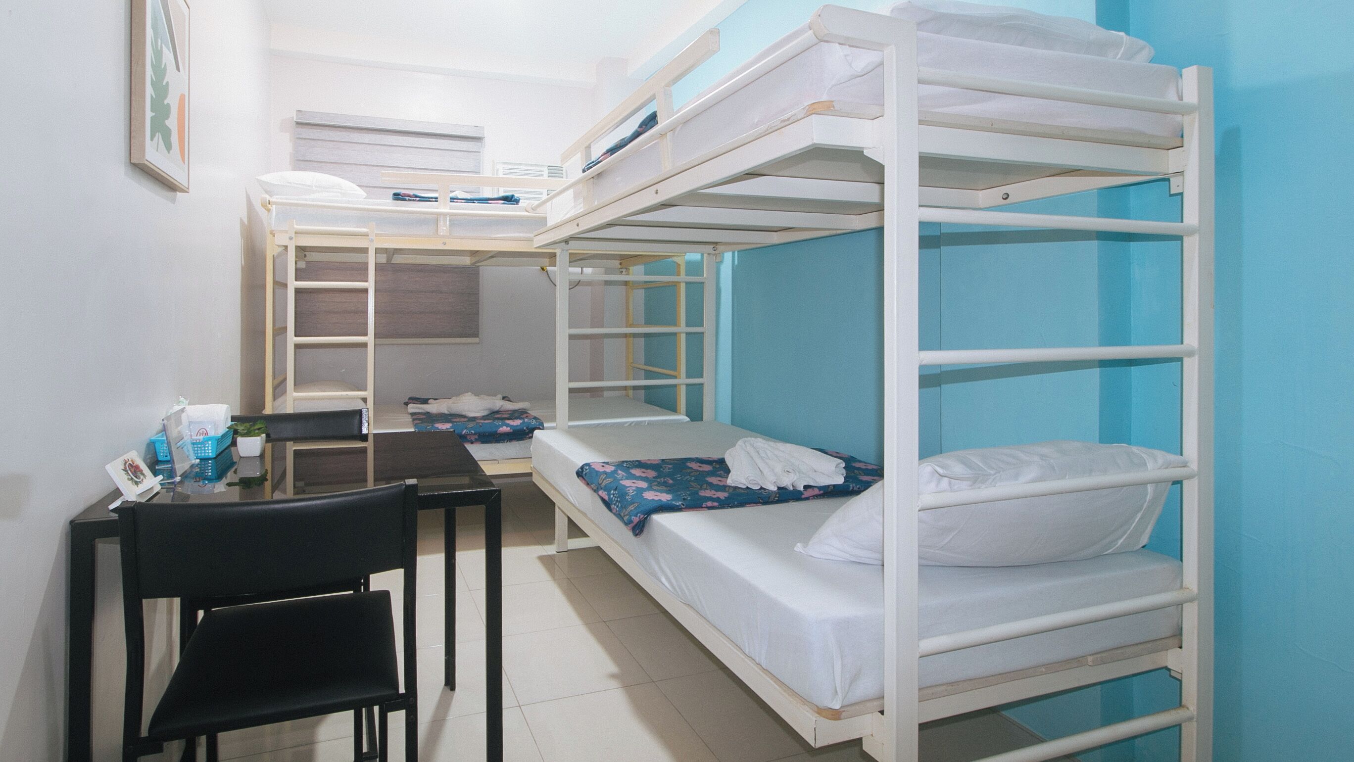 A dormitory room with bunk beds, a desk, and a chair.