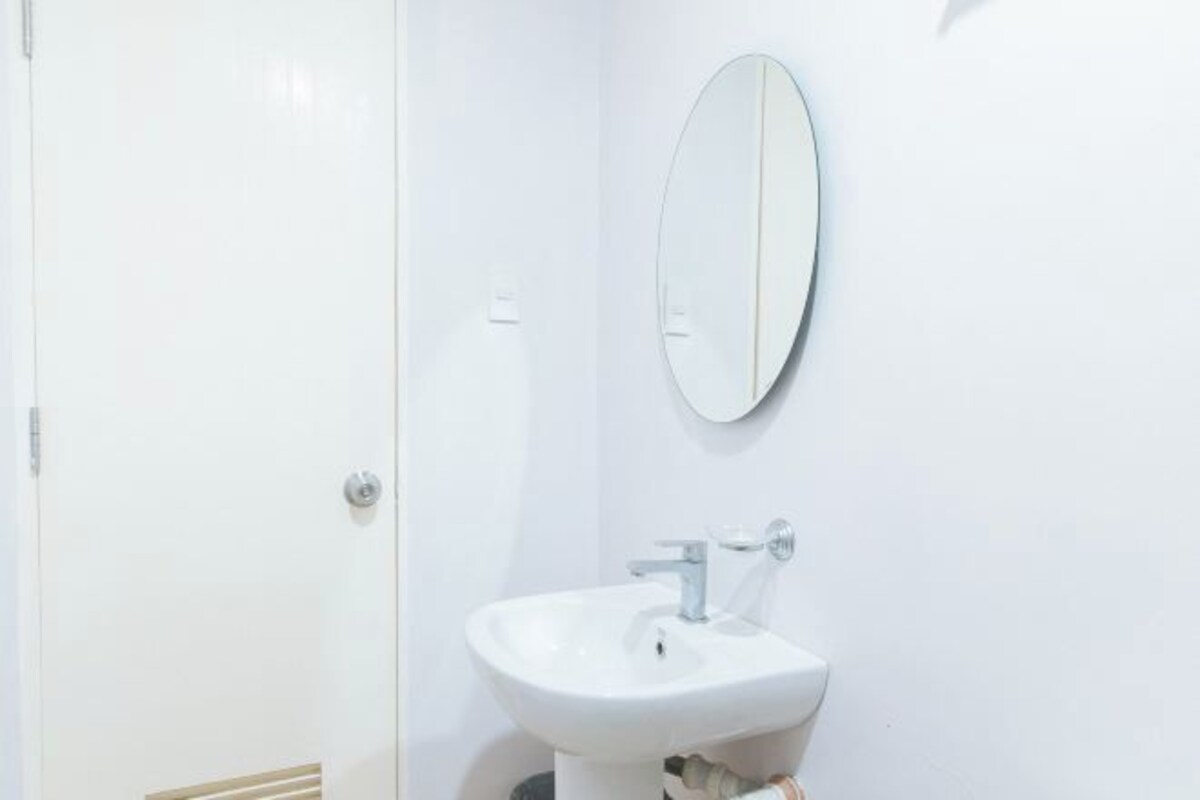 A bathroom with a white sink, a mirror, and a door.