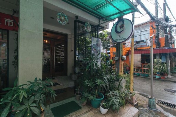 A storefront with a green awning, potted plants, and a signboard. - Catlea Inn (Pasay)