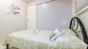 Un dormitorio con cama, almohadas, una obra de arte en la pared y una puerta.