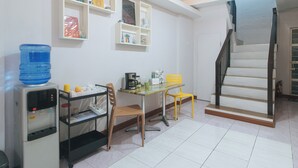 A compact kitchen with a water dispenser, a coffee maker, and a small dining table with chairs. - Catlea Inn (Pasay)