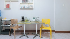 A small dining area with a table, two chairs, a coffee maker, and a mug. - Catlea Inn (Pasay)