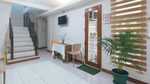 A hotel room with a staircase, a dining area with a table and chairs, a potted plant, and a no-smoking sign. - Catlea Inn (Pasay)