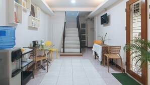 A compact living space with a kitchen area, dining table, and staircase leading to an upper level. - Catlea Inn (Pasay)