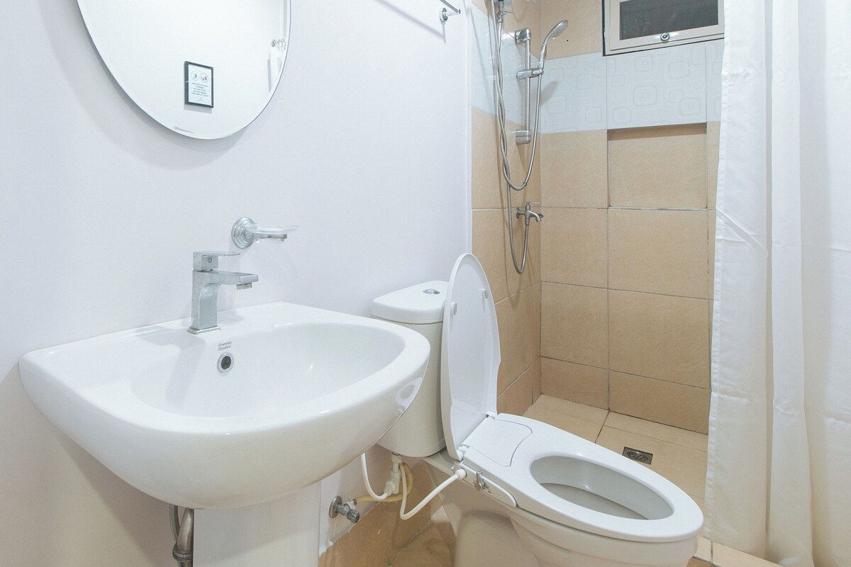 Un baño con lavamanos, inodoro y ducha blancos.