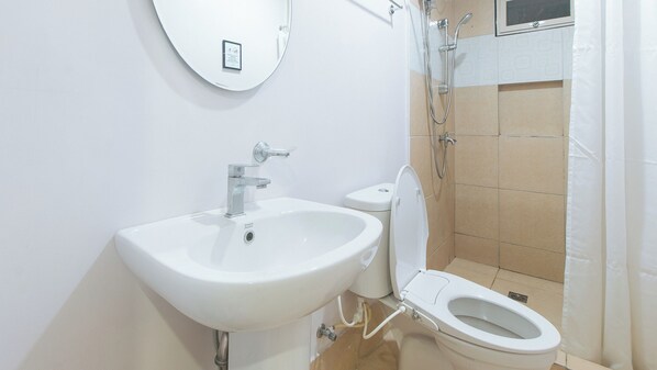 Un baño con lavamanos, inodoro y ducha blancos.