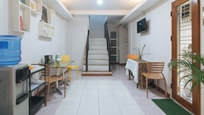 A compact living space with a kitchen area, dining table, and staircase leading to an upper level. - Catlea Inn (Pasay)