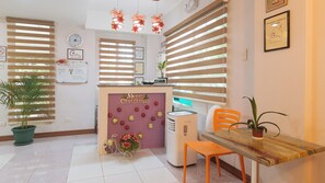 A reception area with a Christmas-themed wall, a reception desk, a clock, and a plant. - Catlea Inn (Pasay)