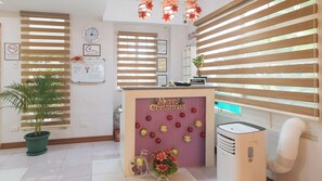 A reception area with a 'Merry Christmas' sign, a clock, and a 'No Smoking' sign. - Catlea Inn (Pasay)