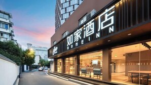 A hotel with a modern facade, large glass windows, and outdoor seating visible through the entrance. - elan hotel(Wulinmen Subway Station Hangzhou Xihu) (Hangzhou)