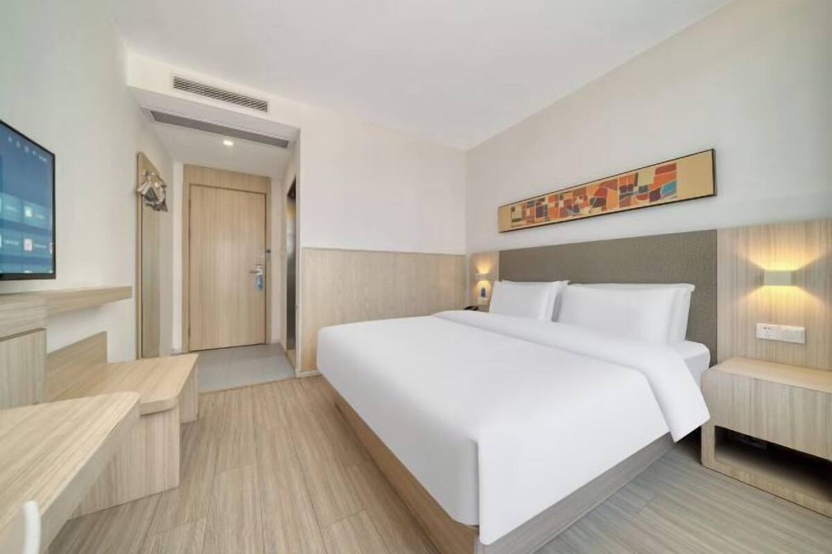 A modern hotel room with a large bed, a desk, and a TV.