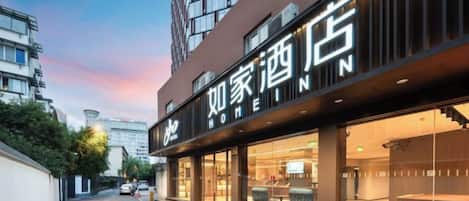 A hotel with a modern facade, large glass windows, and a visible outdoor seating area.
