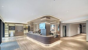 A modern reception area with a curved counter, a digital screen, and a seating area. - elan hotel(Wulinmen Subway Station Hangzhou Xihu) (Hangzhou)