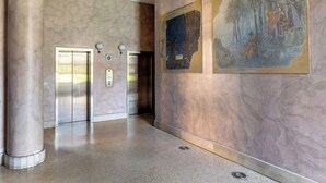 A spacious lobby with marble walls, two elevators, and a large mural. - Una terrazza sulla città by Wonderful Italy (Bologna)