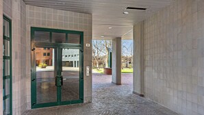 A covered walkway with a tiled floor and a green-framed door leading to a building. - Una terrazza sulla città by Wonderful Italy (Bologna)