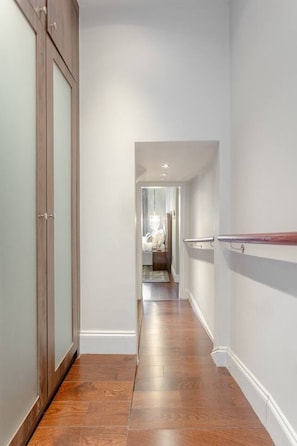 A hallway with wooden flooring, white walls, and a door with a frosted glass panel.