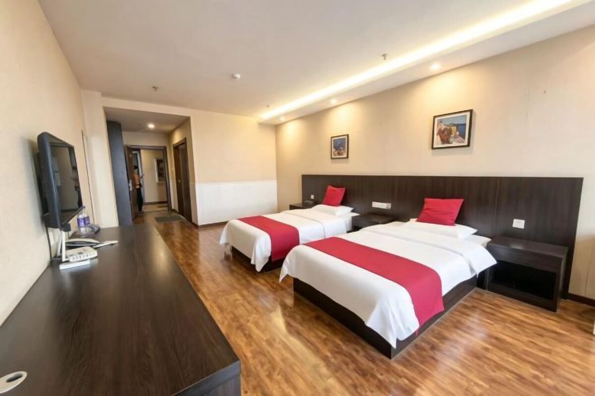 Una habitación de hotel con dos camas, un escritorio y un televisor.