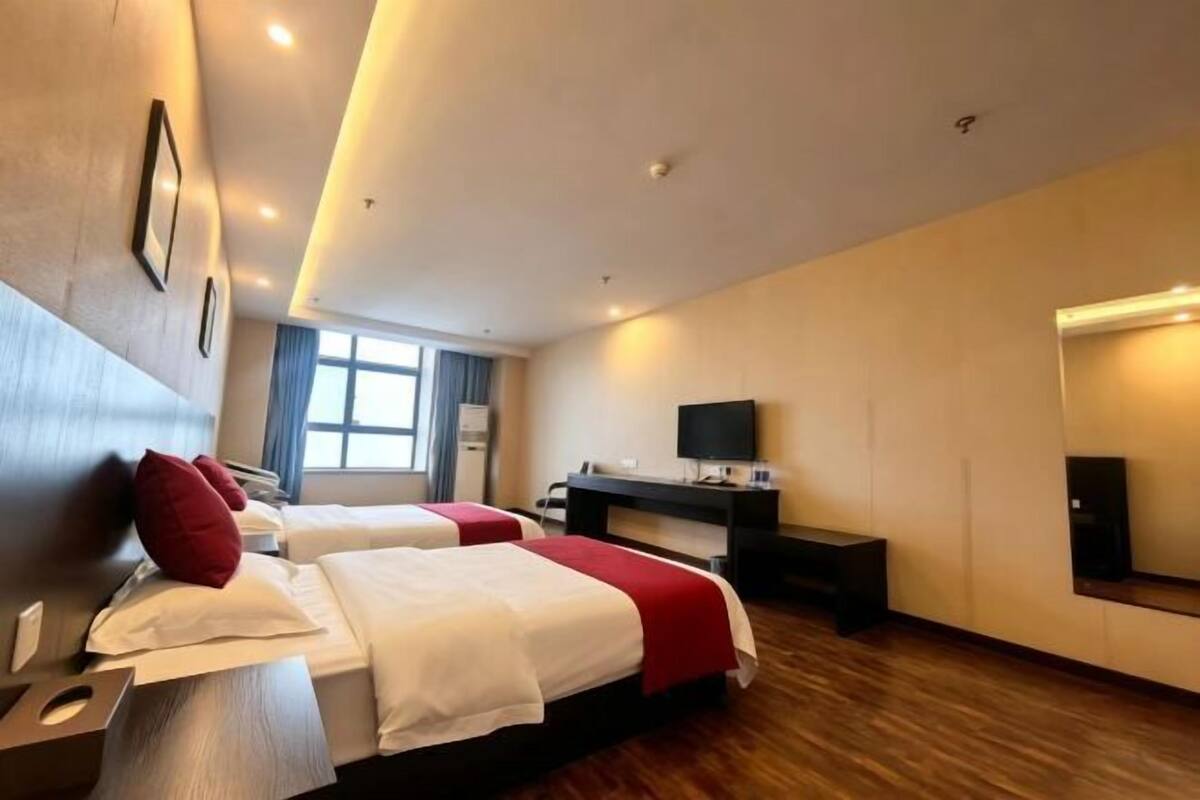 Une chambre d’hôtel avec deux lits, un bureau, une télévision et une grande fenêtre.
