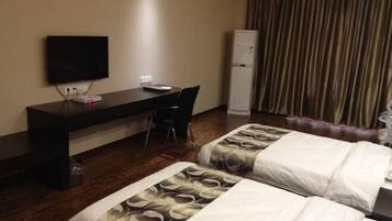 Quarto de hotel com duas camas, uma escrivaninha, uma cadeira, uma televisão e um mini-bar.