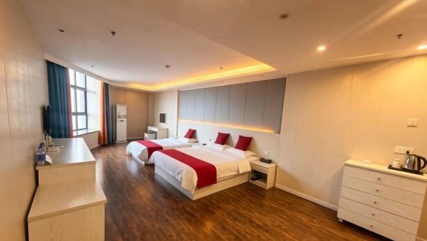 Ein Hotelzimmer mit zwei Betten, einem Schreibtisch, einem Schminktisch und einem großen Fenster.