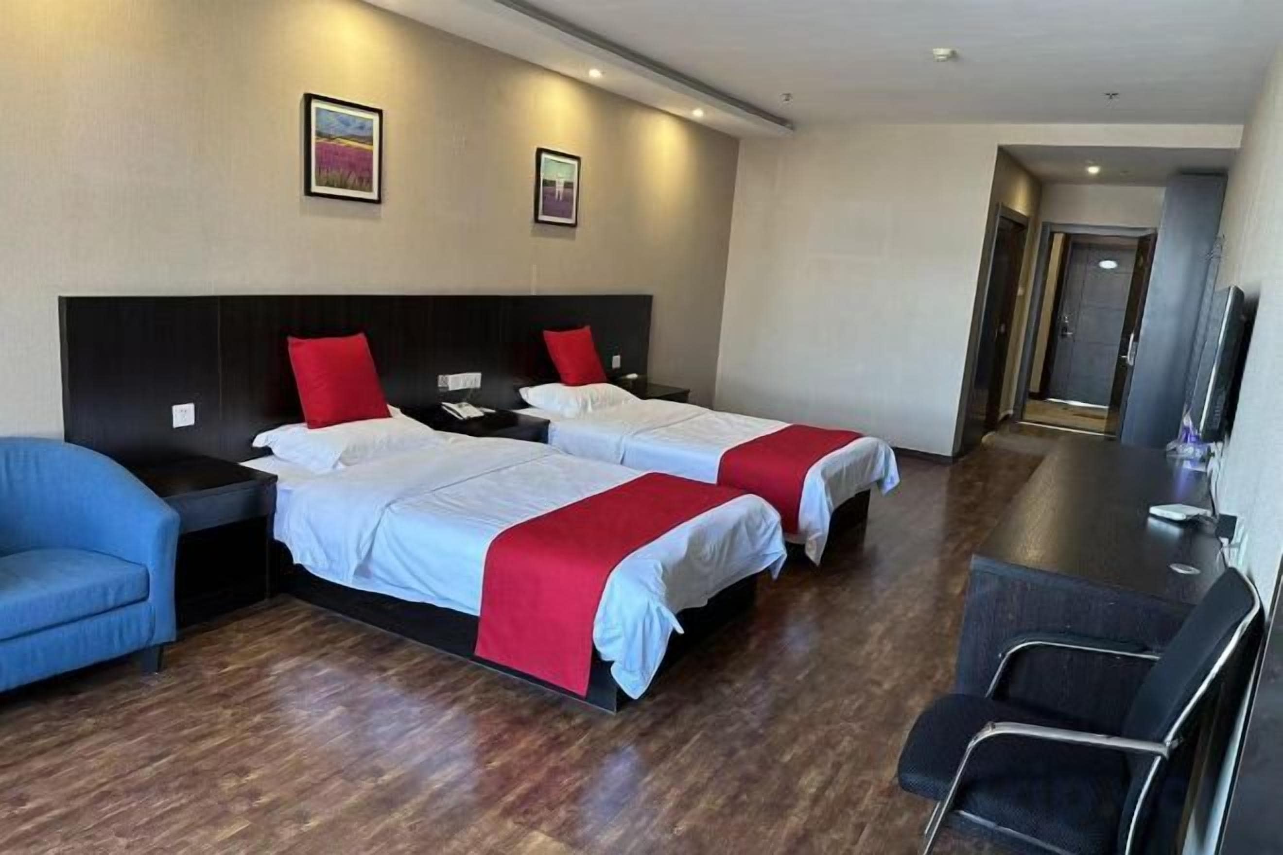 A hotel room with two beds, a desk, a chair, and a television.