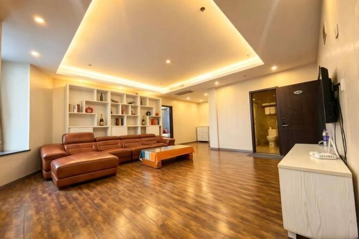 Un salon moderne avec un canapé d’angle, des étagères intégrées et un téléviseur à écran plat.