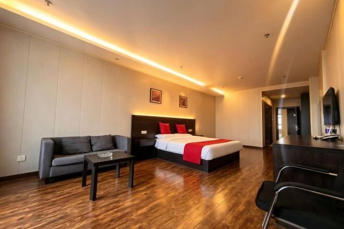 Une chambre d’hôtel avec un lit, un canapé, un bureau et une chaise.