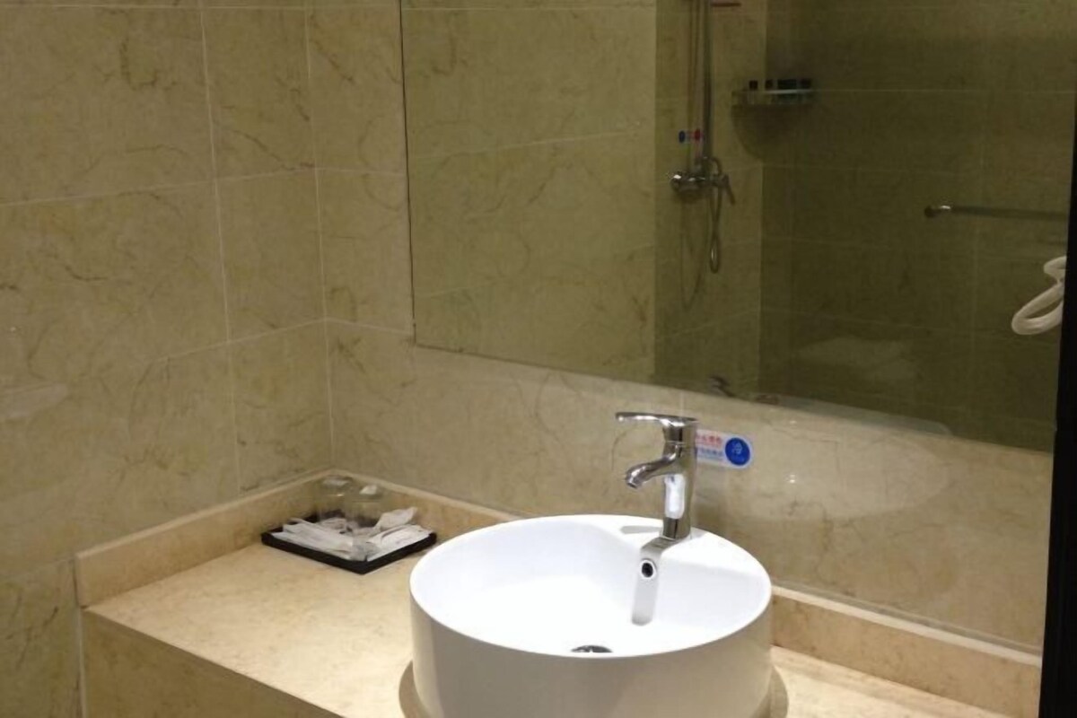 A bathroom with a white sink, a mirror, and a shower.