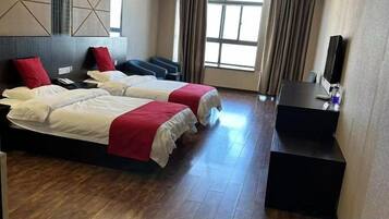 Habitación de hotel con dos camas, un escritorio, un televisor de pantalla plana y un ventanal grande.