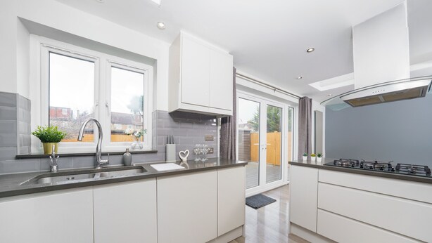 A modern kitchen with white cabinets, a stainless steel sink, and a gas stove. - Beautiful 4 Bedroom House Immaculate Condition. Just Refurbished House. (Romford)