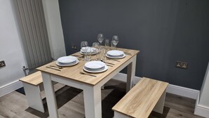 A dining table with white legs and a wooden top, set with plates, cutlery, and glasses. - Beautiful 4 Bedroom House Immaculate Condition. Just Refurbished House. (Romford)